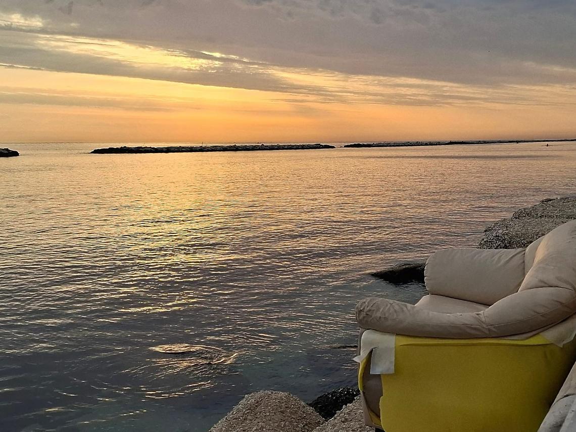 Un divano abbandonato sugli scogli del lungomare di Bari